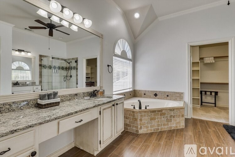 A spacious bathroom with a large tub and a vanity with a mirror.