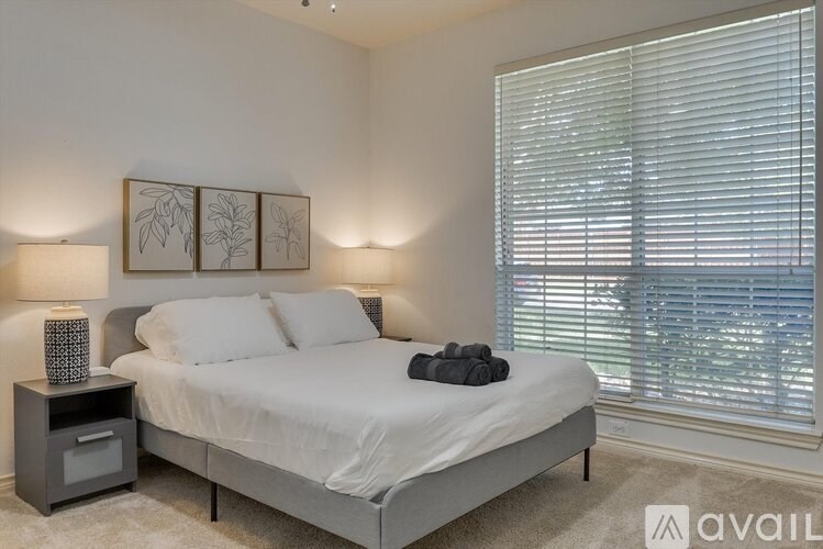 A bedroom with a large bed and two lamps.