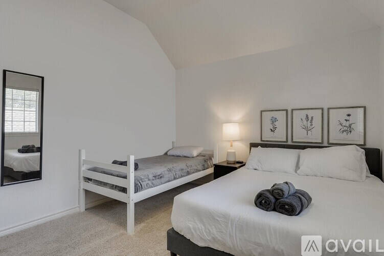 A bedroom with a white bed and a mirror on the wall.
