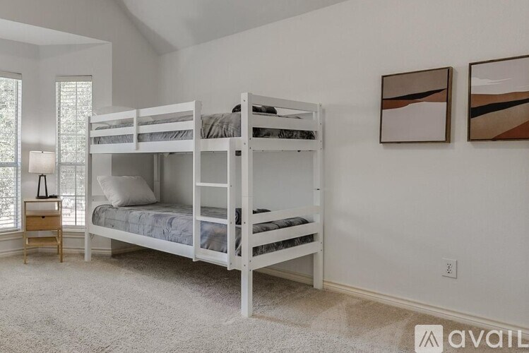 A bedroom with white walls and carpet has two bunk beds.