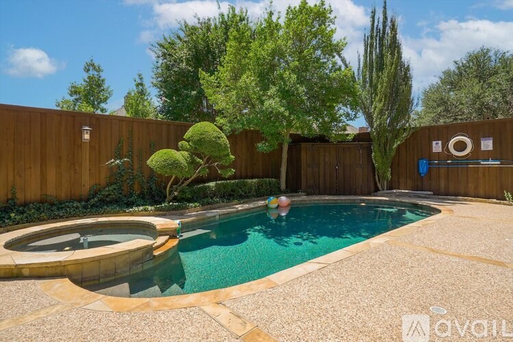 A person is swimming in a pool surrounded by a wooden fence and trees.
