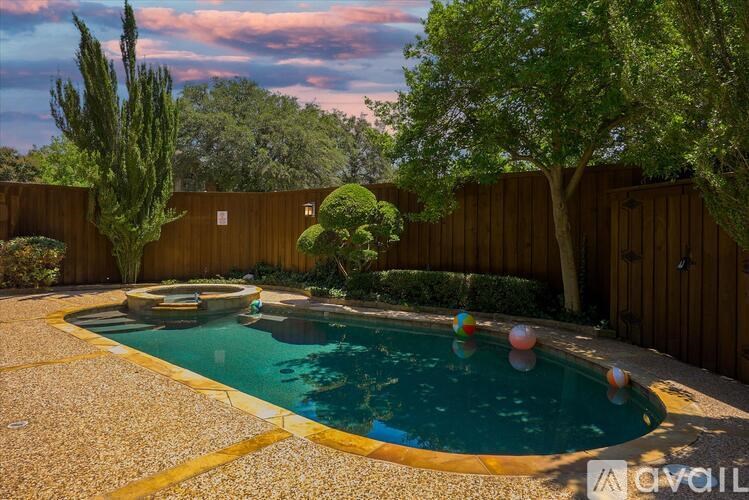 A pool surrounded by a wooden fence and trees.