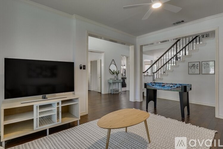 A living room with a television, a coffee table, and a staircase in the background.