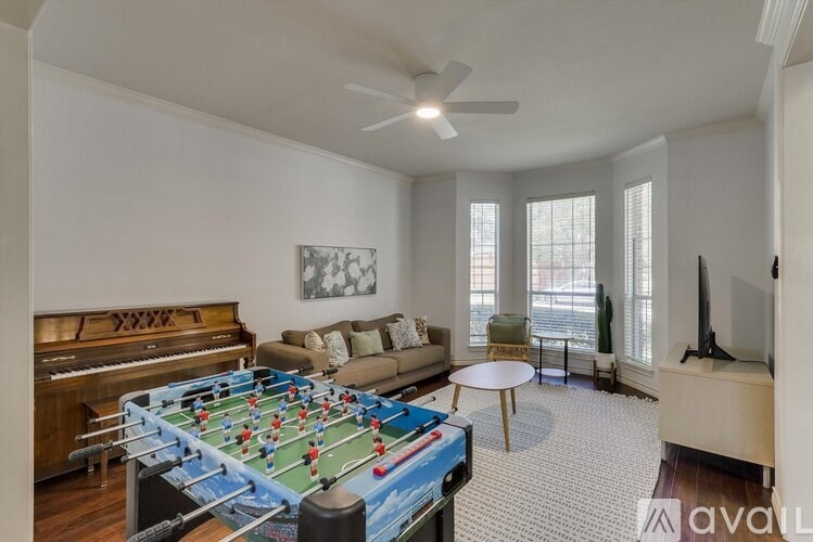 A room with a foosball table, a couch, a television, and a piano.