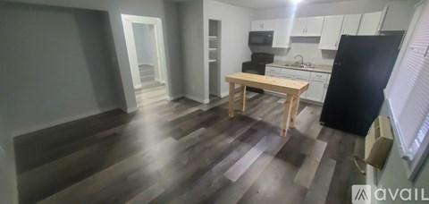 A kitchen with a black refrigerator and wooden table.