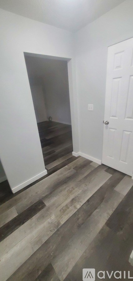 A room with a white door and a wooden floor.