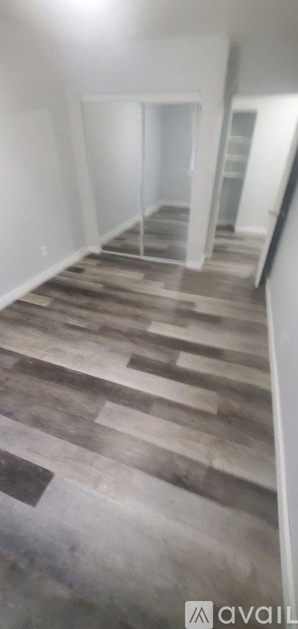 A room with wooden flooring and white walls.