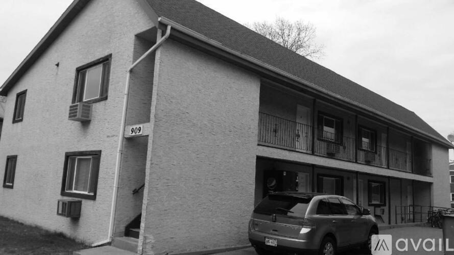 A black and white photo of a house with a car parked in front.