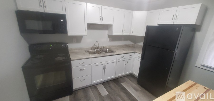 A kitchen with black appliances and white cabinets.