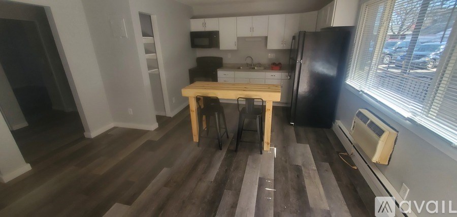 A kitchen with a black fridge and wooden floors.