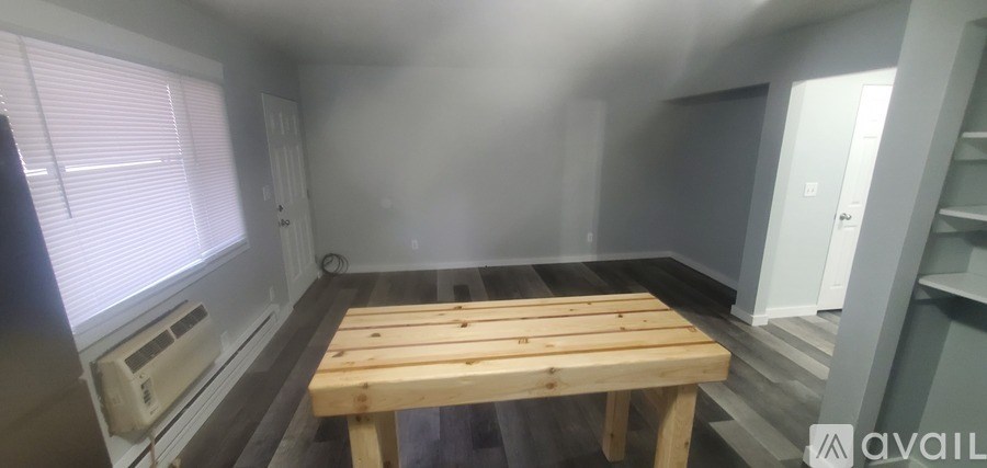 A room with a wooden table and a window with blinds.