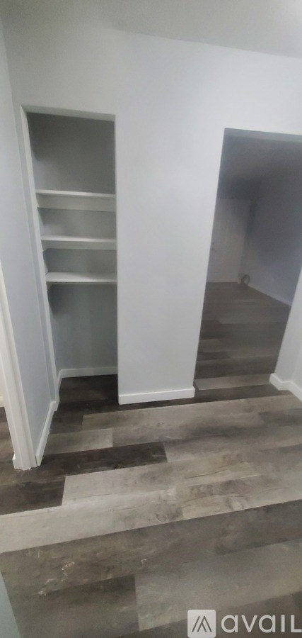 A room with a staircase and a wall with shelves.