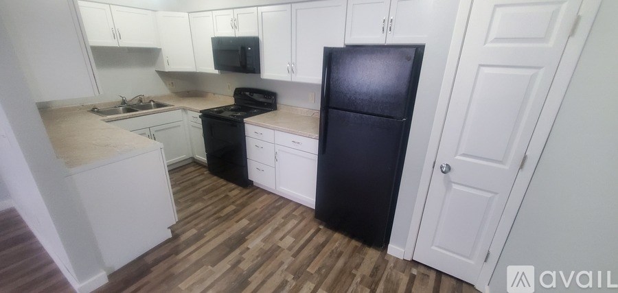 A kitchen with white cabinets and a black fridge.