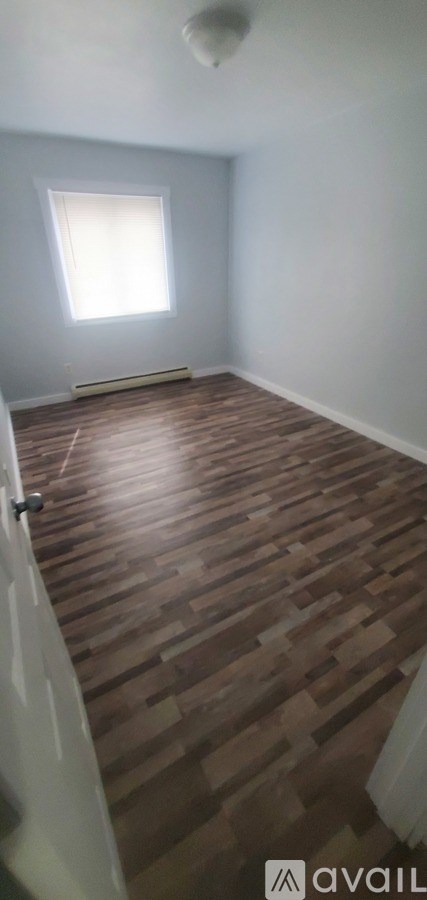 A room with wooden flooring and a window.