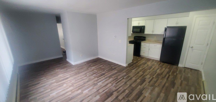 A kitchen with a black fridge and wooden floors.