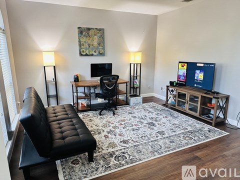 A living room with a black leather chair and a rug.