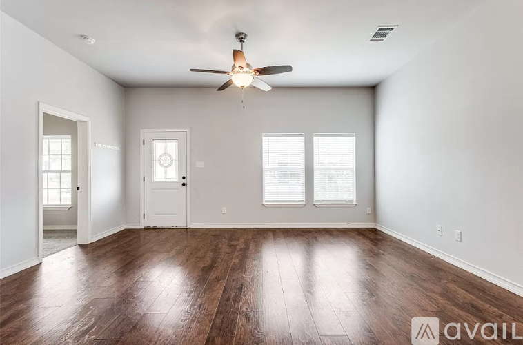 A room with a ceiling fan and wooden flooring.