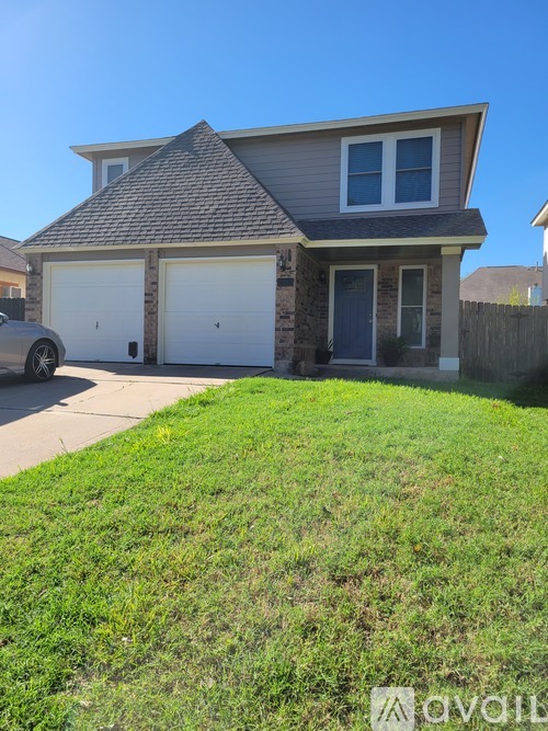 A house with a grey roof and two garage doors.