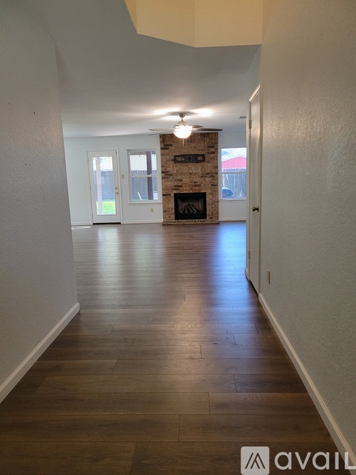 A long hallway with a stone fireplace and wood floors.
