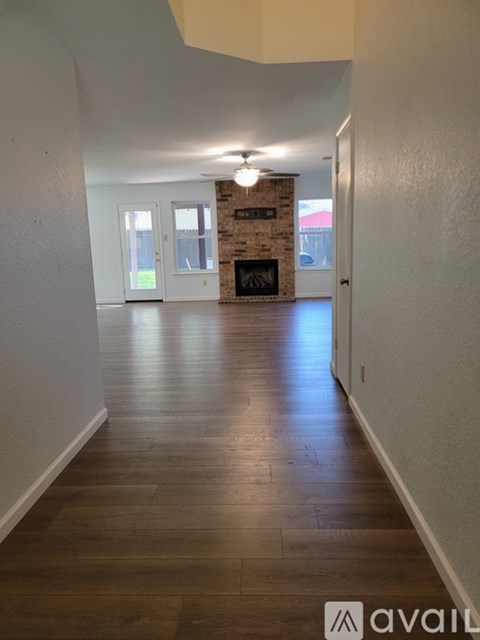 A long hallway with a stone fireplace and wood floors.