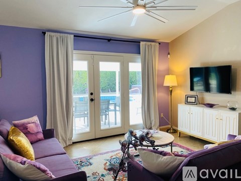 A living room with a purple couch and a ceiling fan.