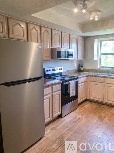 A kitchen with a stainless steel refrigerator and wooden cabinets.