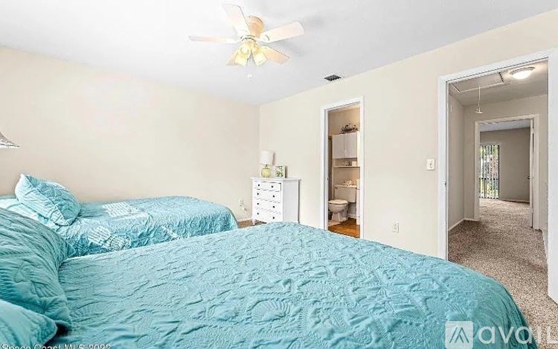 A bedroom with two beds and a ceiling fan.