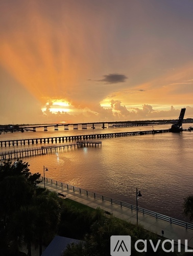 A sunset view with a bridge and a plane in the sky.