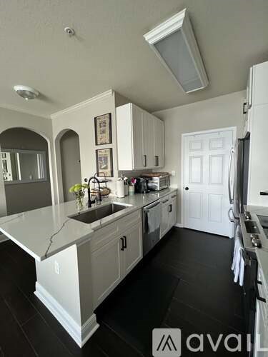 A kitchen with white cabinets and a black floor.