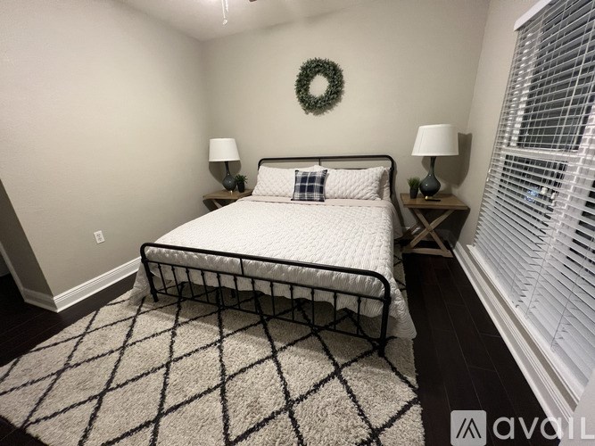 A bedroom with a bed, two lamps, and a wreath on the wall.