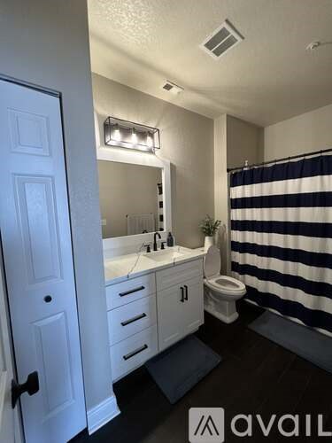 A bathroom with a striped shower curtain and a white door.