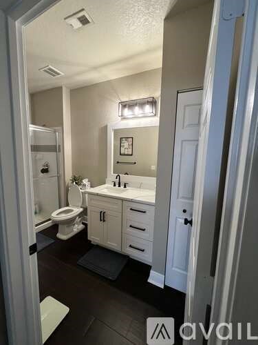 A bathroom with a toilet, sink, and mirror.