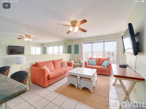 A living room with a red couch and a ceiling fan.