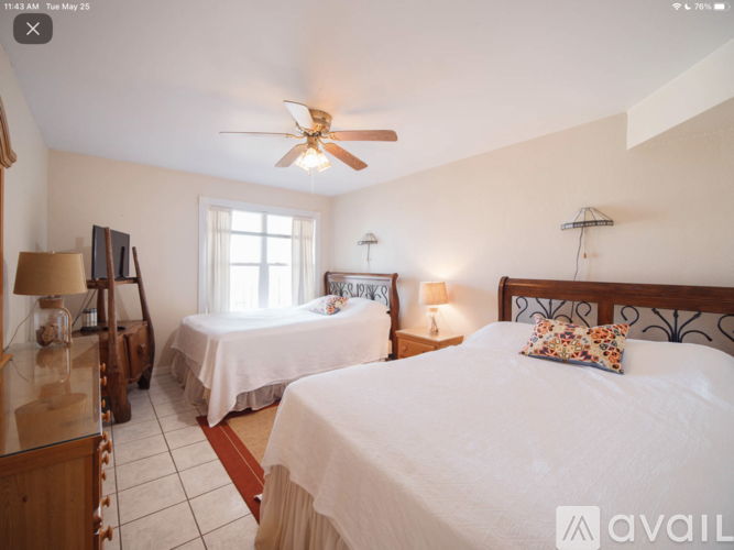 A bedroom with two beds and a ceiling fan.