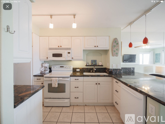 A kitchen with white cabinets and a black countertop.