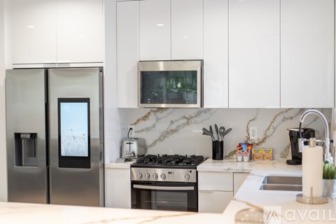 A modern kitchen with a stainless steel refrigerator and a marble backsplash.