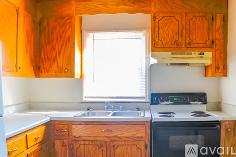 A kitchen with wooden cabinets and a white stove top oven.