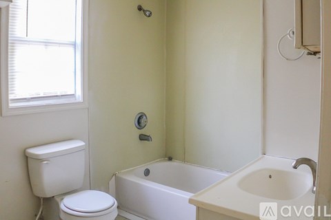 A white toilet sits next to a white bathtub in a bathroom.