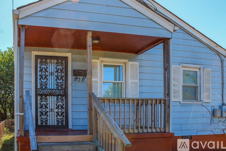 A small blue house with a porch and a door with a decorative grill.