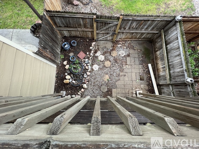 A wooden deck leads to a rustic wooden shed with a roof made of corrugated metal sheets.