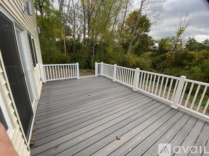 A deck with white railings and a view of trees.