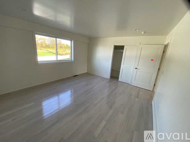 A spacious room with wooden flooring and white walls.