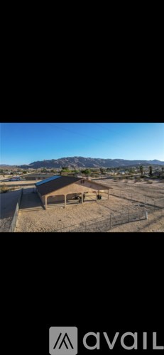 A building with a roof and a fence in the foreground with mountains in the background.
