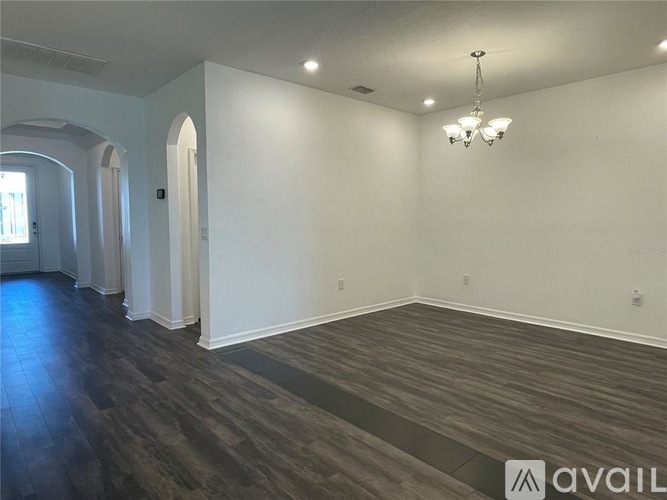 A spacious room with a chandelier and arched doorways.