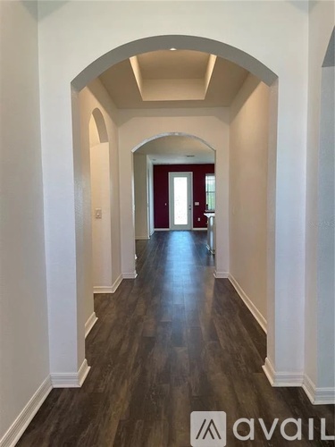 A hallway with arched doorways and wood flooring.