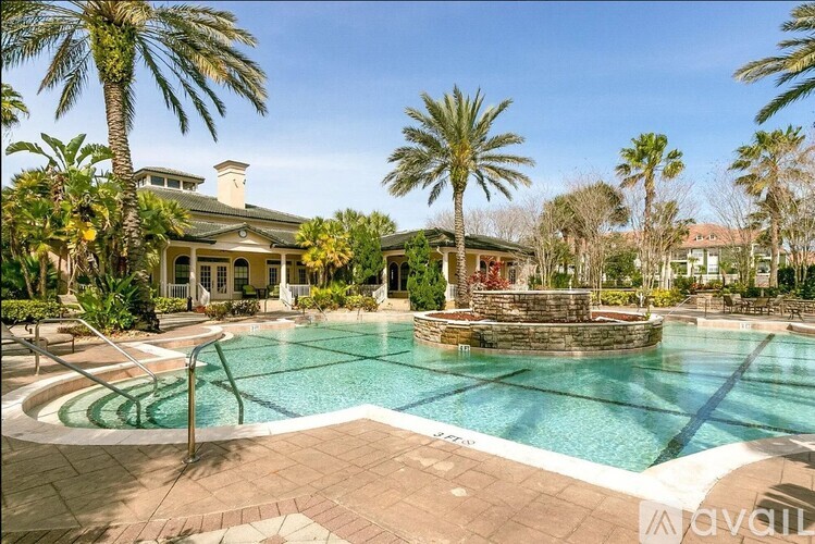 A large outdoor swimming pool surrounded by palm trees and a stone fountain.