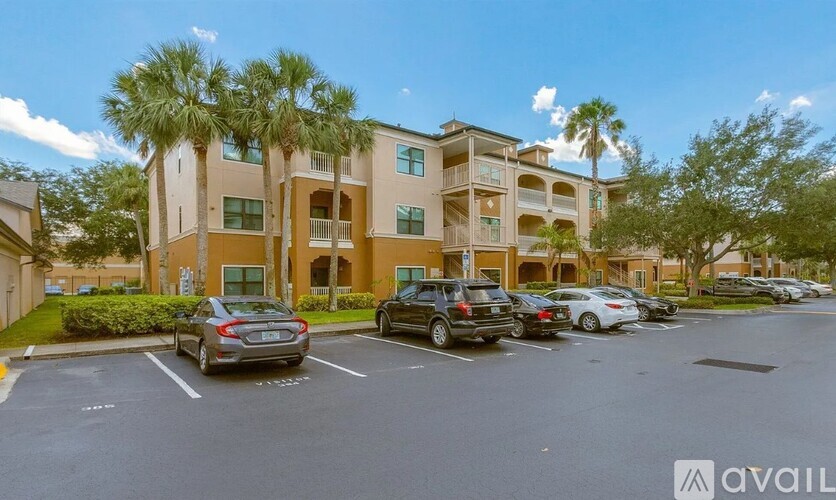 A parking lot with cars and a building with palm trees in front.