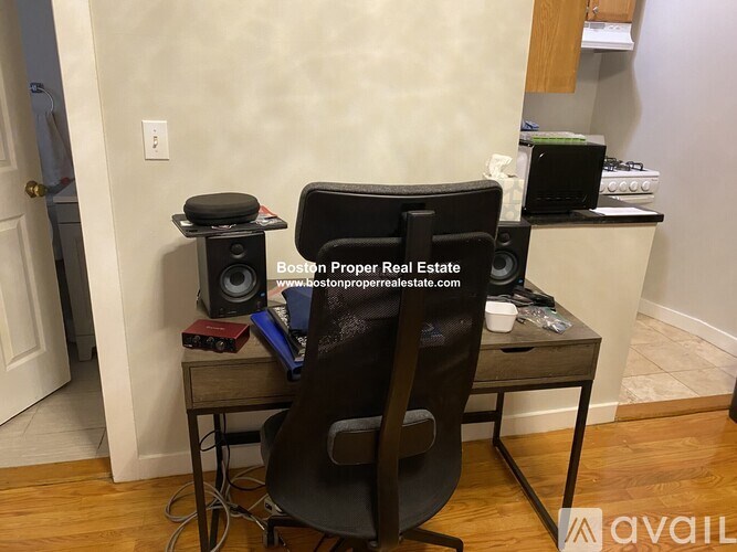 A black leather chair is in front of a desk with a computer and other items.