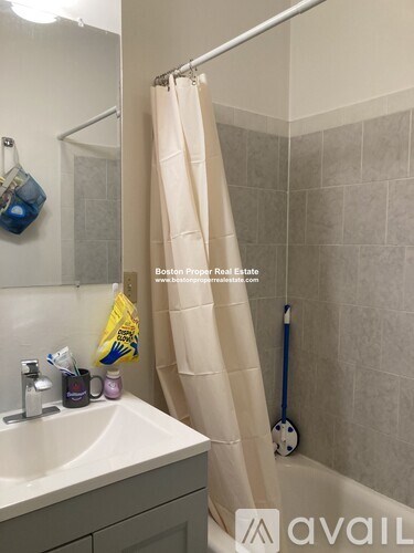 A bathroom with a sink, shower curtain, and a broom.