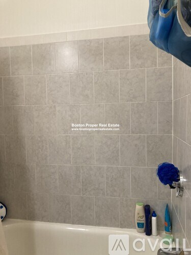 A bathroom with a tiled wall and a white bathtub.